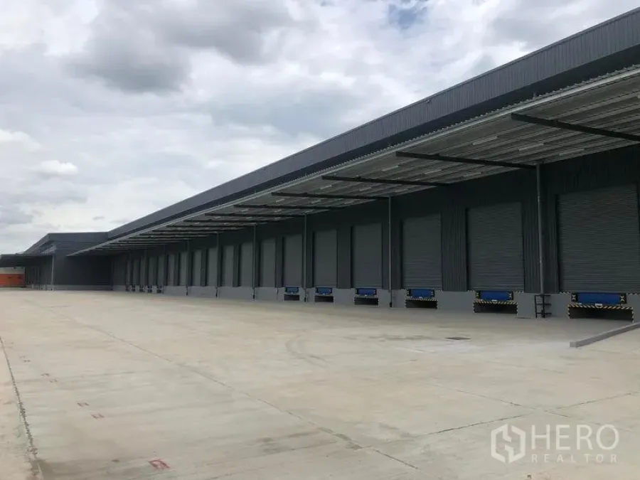 Factory for rent in Wang Noi, Phra Nakhon Si Ayutthaya - Long covered loading dock with multiple roller shutter doors and a wide truck apron.