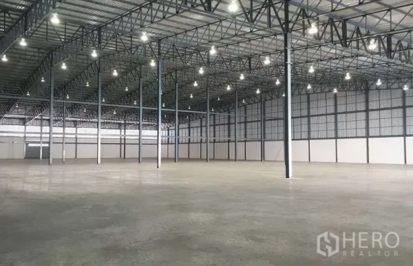 Warehouse for rent in Mueang Samut Prakan, Samut Prakan - Spacious warehouse interior with high steel-truss roof, bright bay lighting and concrete floor.