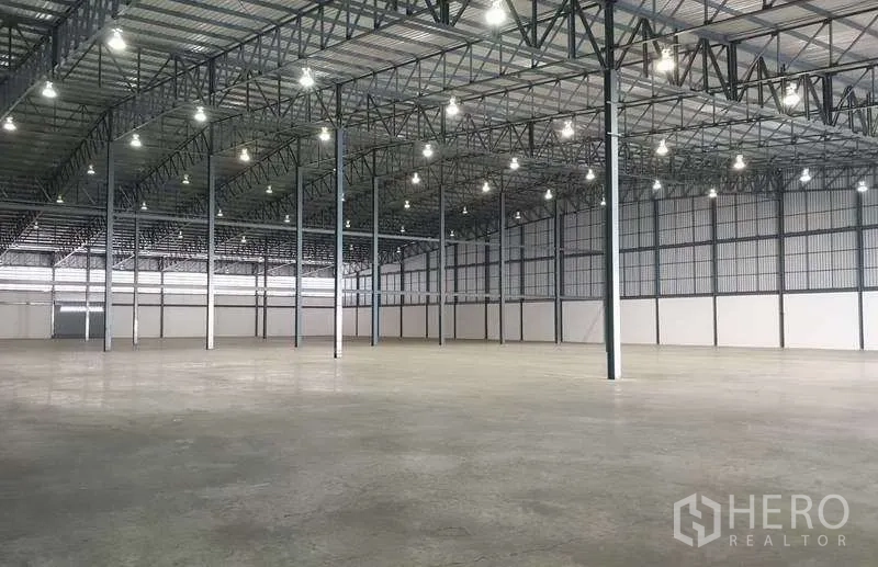 Warehouse for rent in Mueang Samut Prakan, Samut Prakan - Spacious warehouse interior with high steel-truss roof, bright bay lighting and concrete floor.