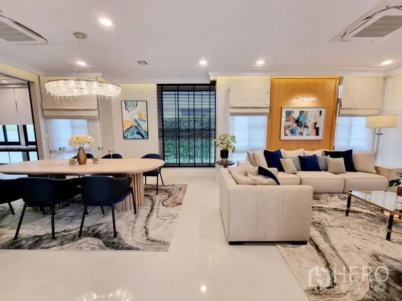 Detached House for rent in Saphan Sung, Bangkok - Open-plan living and dining area with chandelier, sectional sofa, and floor-to-ceiling windows.