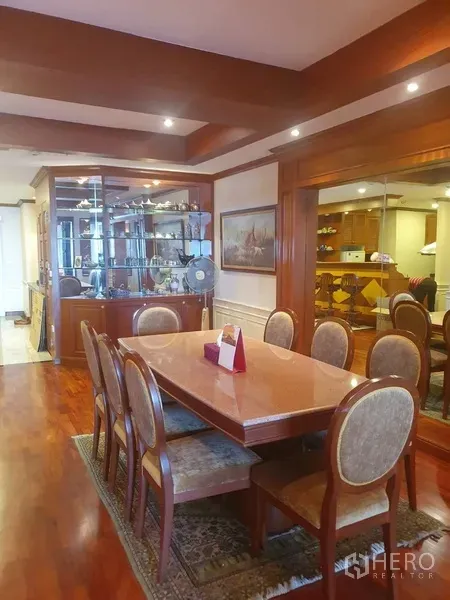 Condominium for rent in Bang Kho Laem, Bangkok - Formal dining area with eight-seat wooden table, glass display cabinet, recessed lighting and polished hardwood floors.
