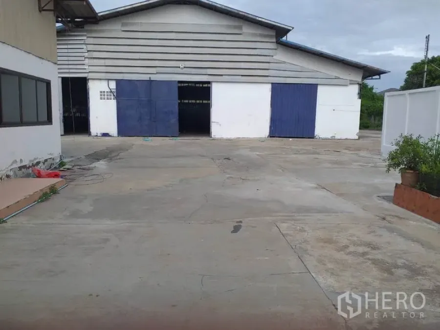 คลังสินค้า ให้เช่าในPak Kret, Nonthaburi - ภายนอกโกดังที่ปากเกร็ด ประตูบานเลื่อนสีน้ำเงิน-ขาว พร้อมลานคอนกรีตกว้างสำหรับขนถ่ายสินค้า
