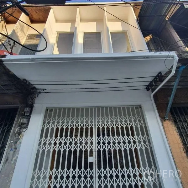 Shophouse for rent or sale in Khlong Toei, Bangkok - Freshly painted shophouse facade with tall upper windows and a metal folding gate.