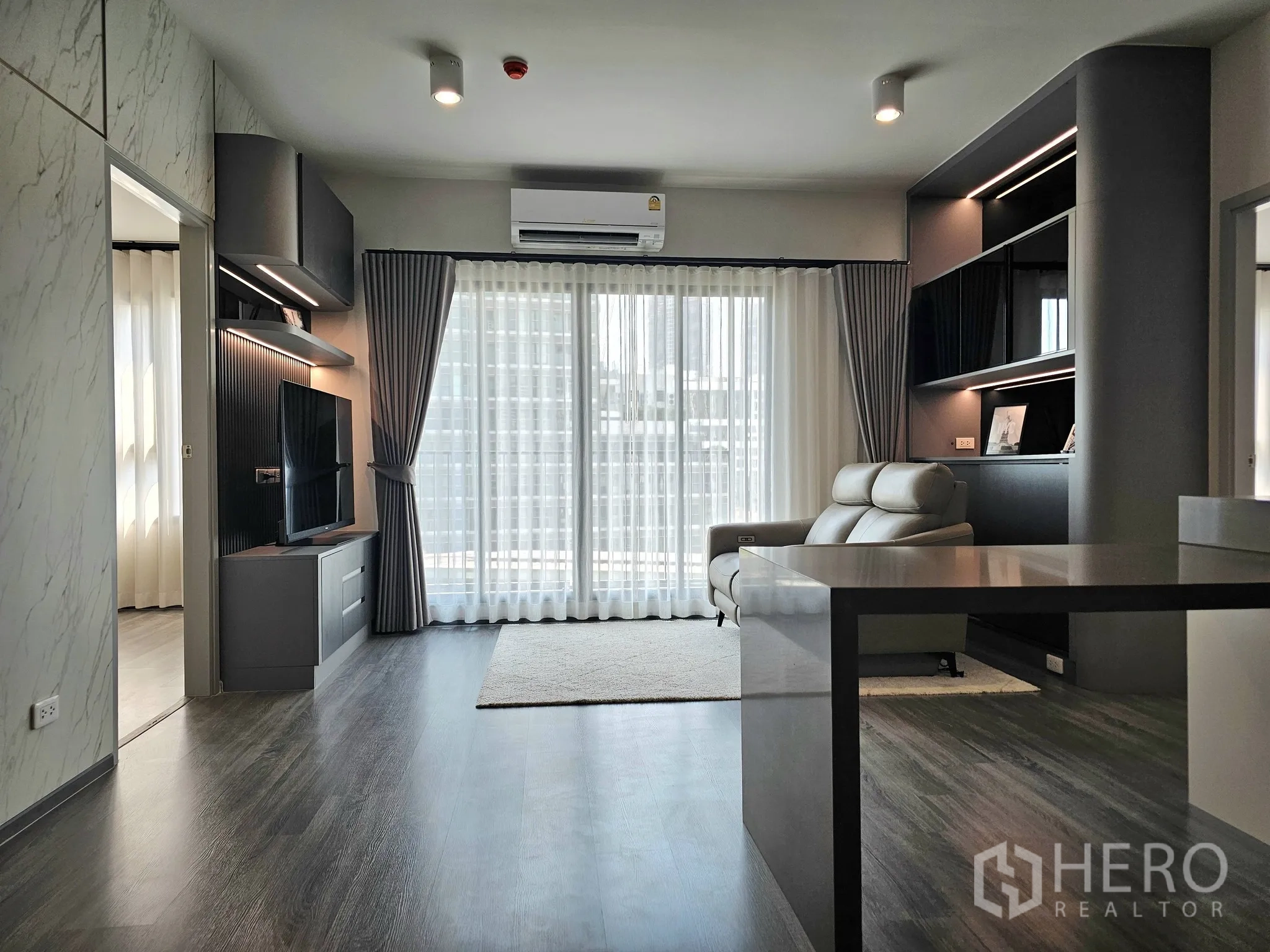 公寓 for sale in Bang Rak, Bangkok - 现代客厅设电视墙与置物架，大幅推拉玻璃门与窗帘。