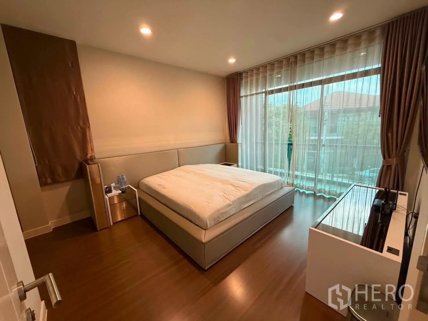 Detached House for rent in Bang Kapi, Bangkok - Cozy bedroom with a king bed and full-height glazing with sheer curtains.