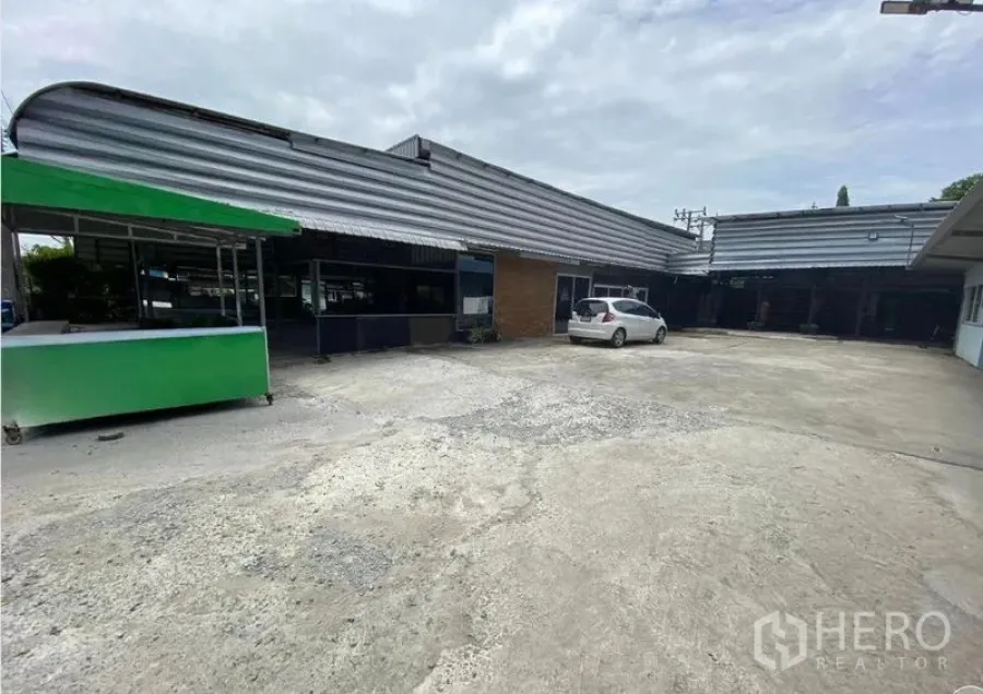 Warehouse for rent in Mueang Nonthaburi, Nonthaburi - Low-rise warehouse exterior with wide concrete yard, covered bays, and onsite parking.