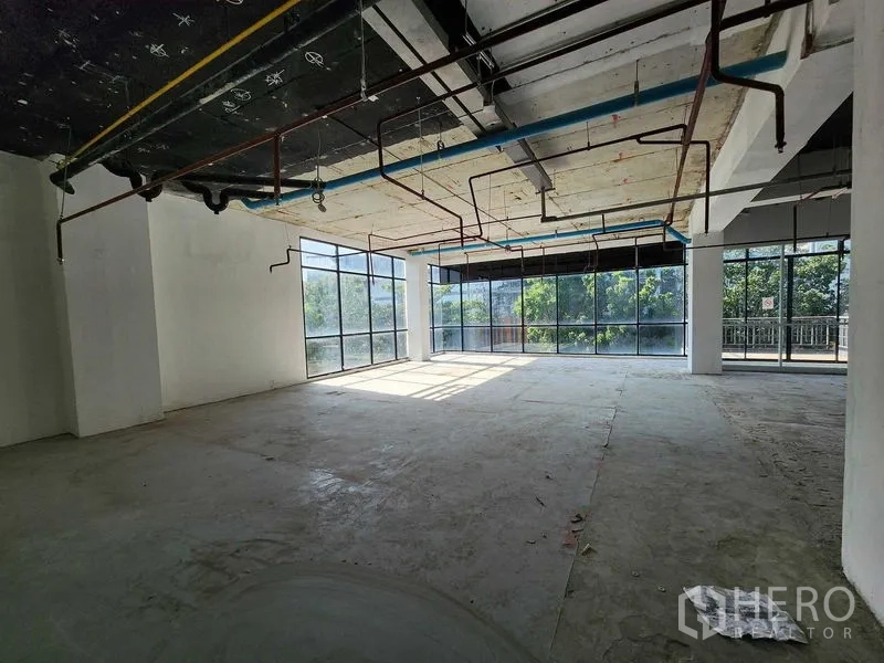 零售空间 出租在Sathon, Bangkok - 采光充足的转角零售空间，落地窗、外露管线与混凝土地面，面向绿景