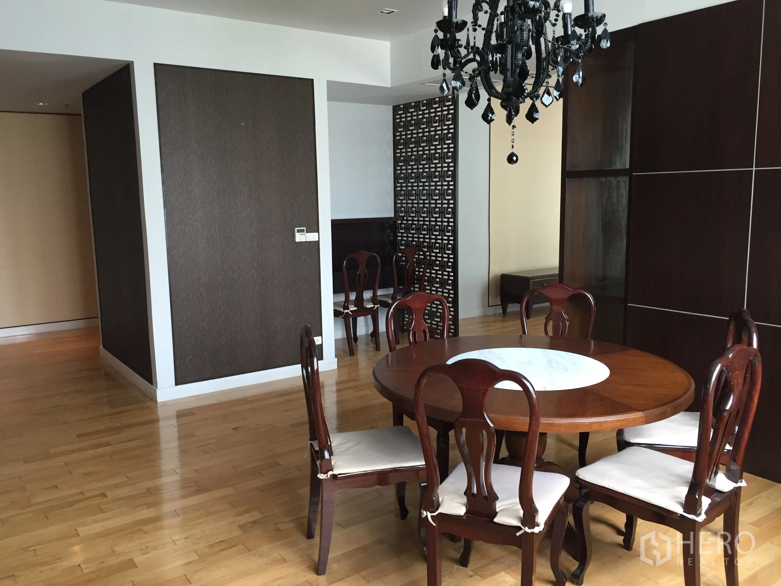 Condominium for rent or sale in Khlong Toei, Bangkok - Dining area with round wooden table, six chairs, chandelier and light wooden flooring.