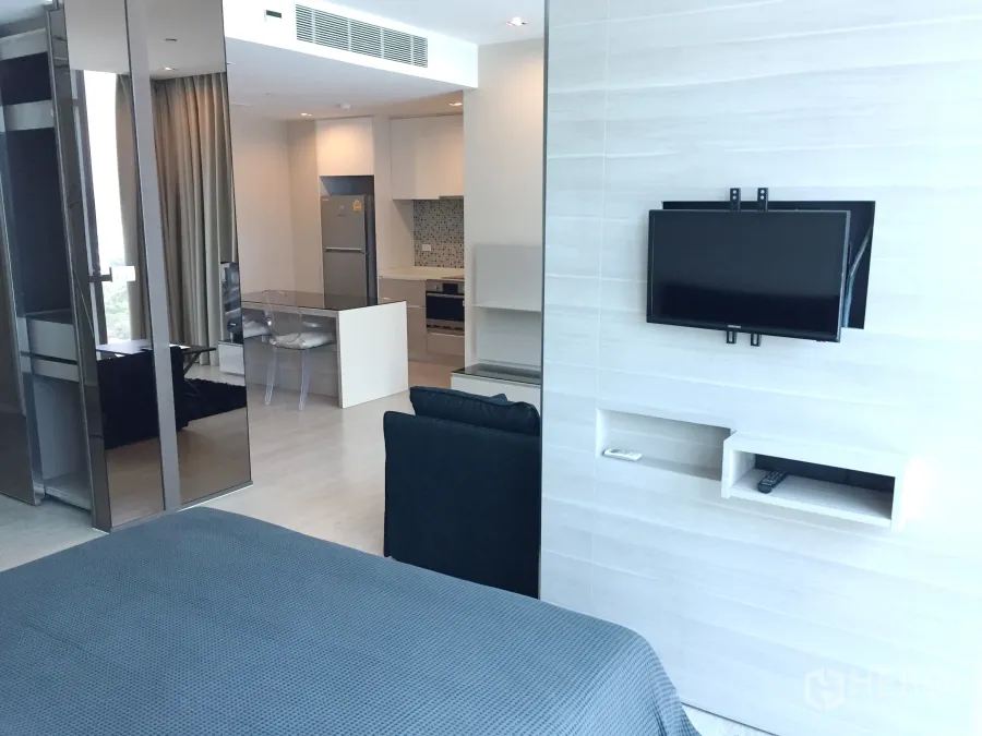 公寓 出租在Watthana, Bangkok - 明亮的一卧室公寓内景，墙挂电视、滑动玻璃隔断与开放式厨房餐区。