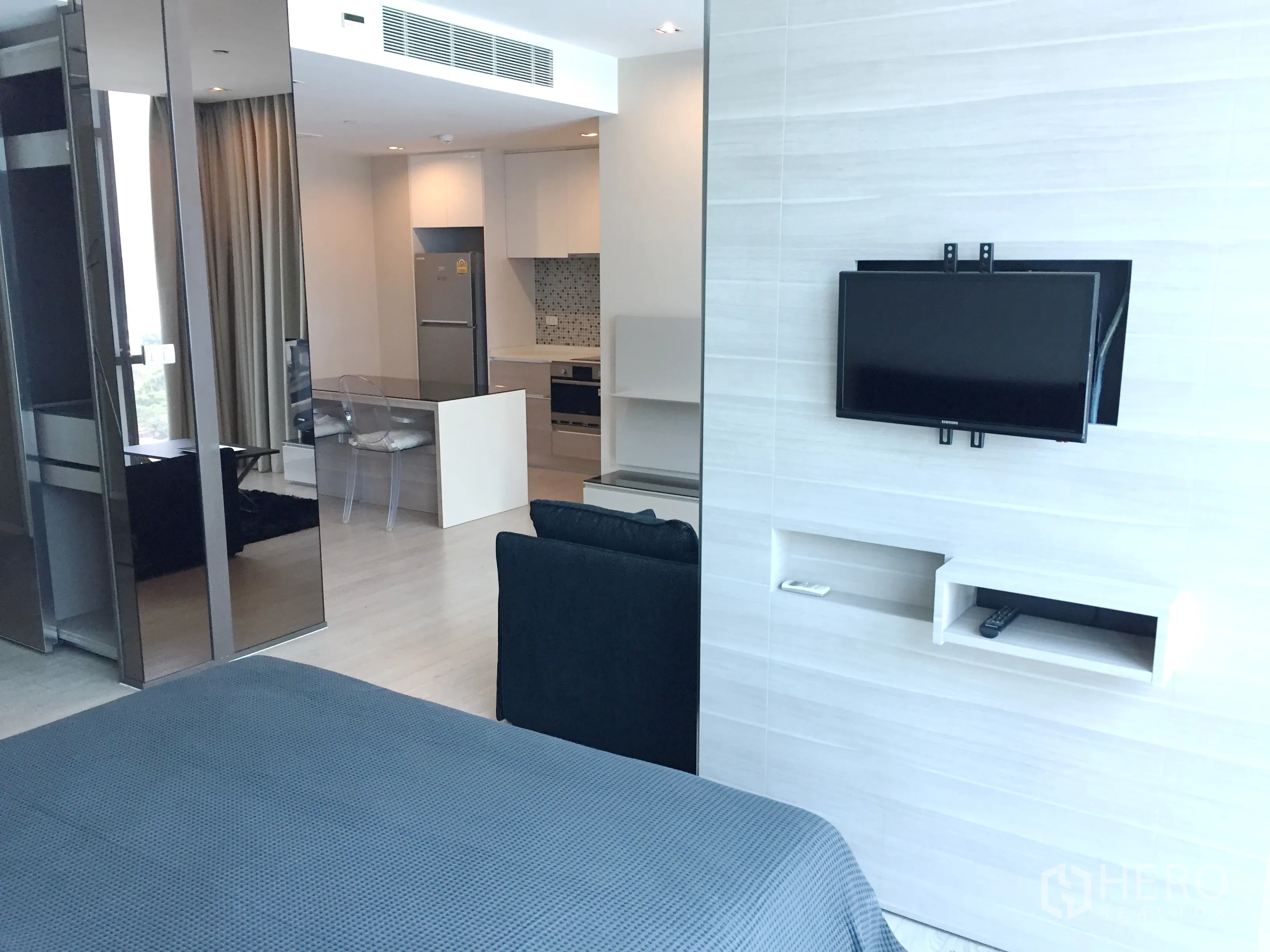 公寓 出租在Watthana, Bangkok - 明亮的一卧室公寓内景，墙挂电视、滑动玻璃隔断与开放式厨房餐区。