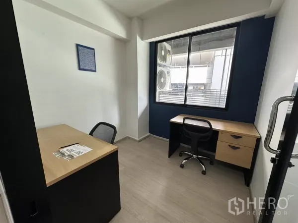 办公空间 出租在Watthana, Bangkok - 紧凑双工位办公室，带大窗，海军蓝特色墙与复合地板。