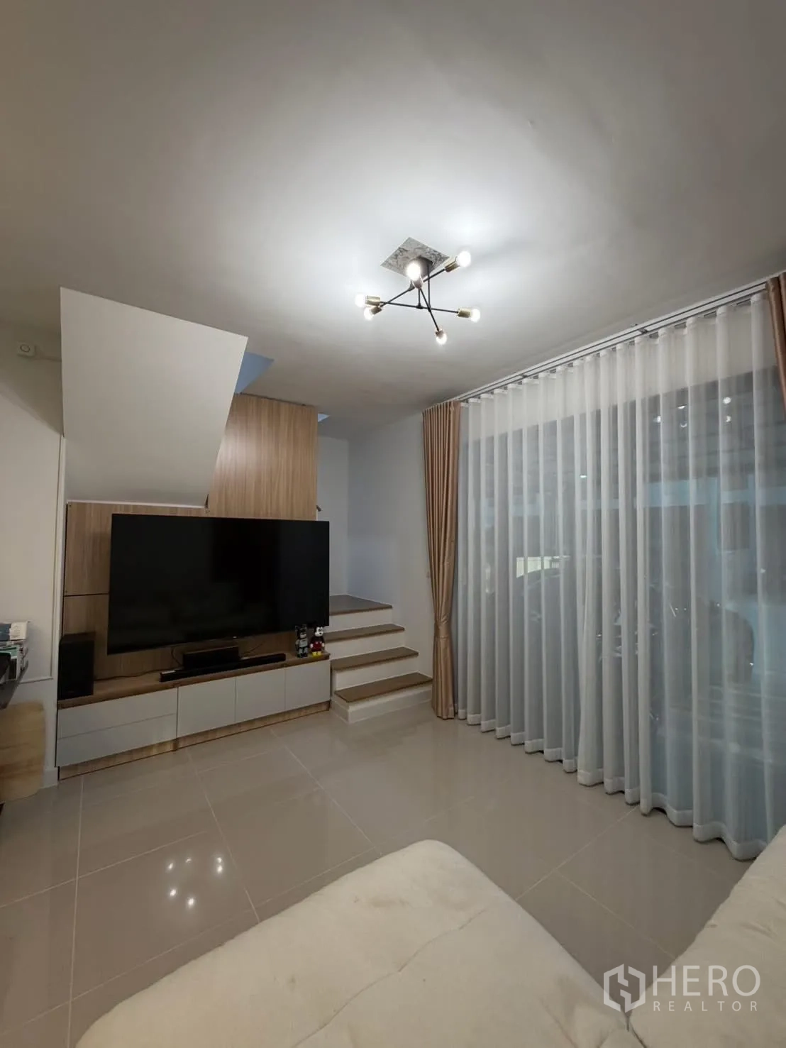 联排别墅 for rent in Bang Phli, Samut Prakan - 电视背景墙配超大屏与纱帘，旁为楼梯细节。