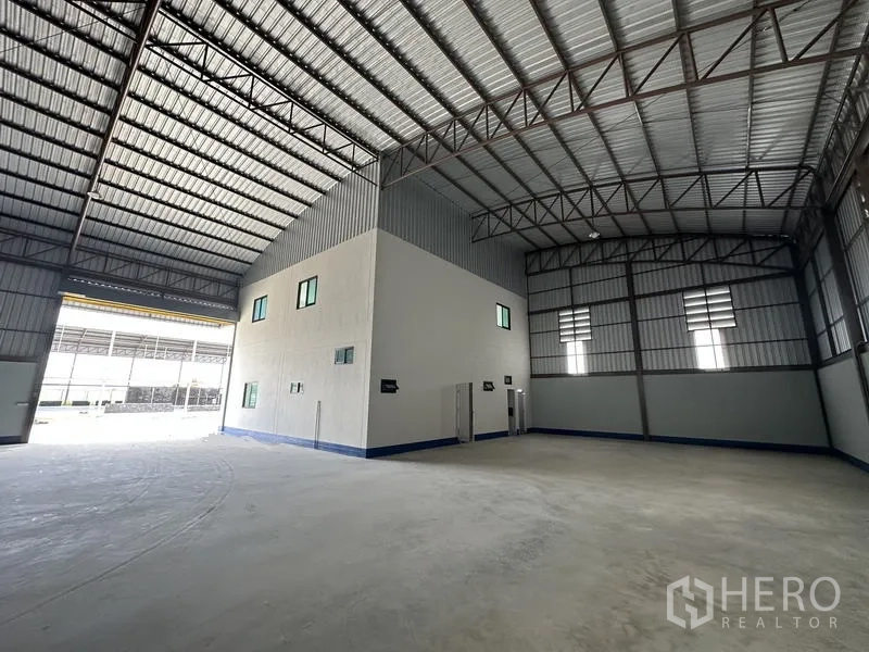 Factory for rent or sale in Sai Noi, Nonthaburi - Industrial hall showing office core, ventilation panels and wide loading doorway.