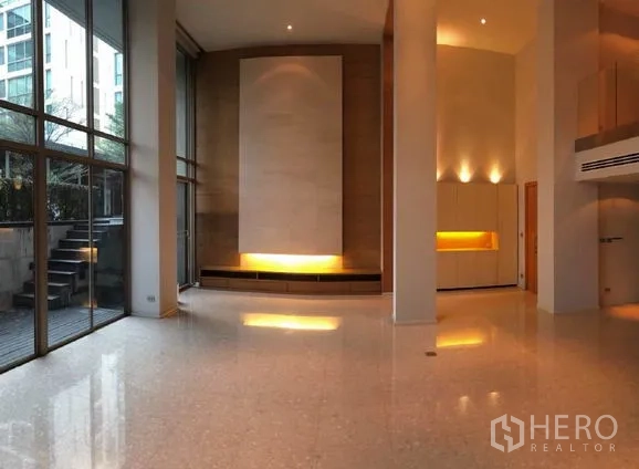 Condominium for sale in Khlong Toei, Bangkok - Bright living room with floor-to-ceiling windows, feature wall lighting and steps to a private terrace.