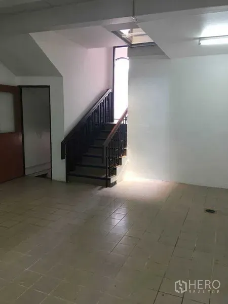 联排别墅 出租在Phra Khanong, Bangkok - 一层瓷砖地面与锻铁扶手楼梯，窗边采光充足。