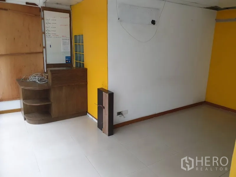 Retail Space for rent in Watthana, Bangkok - Small retail room with white and yellow walls, tiled floor and a built-in wooden counter.