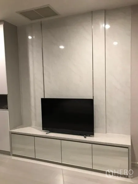 Condominium for rent in Pathum Wan, Bangkok - Living area with sleek TV console and marble accent wall