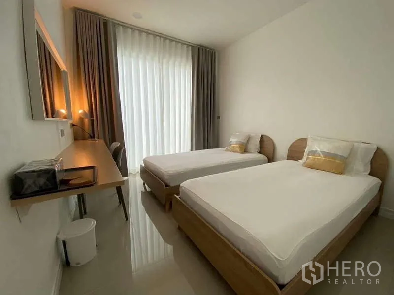 Detached House for rent in Lat Krabang, Bangkok - Cozy bedroom with two single beds, blackout drapes and a long study desk.