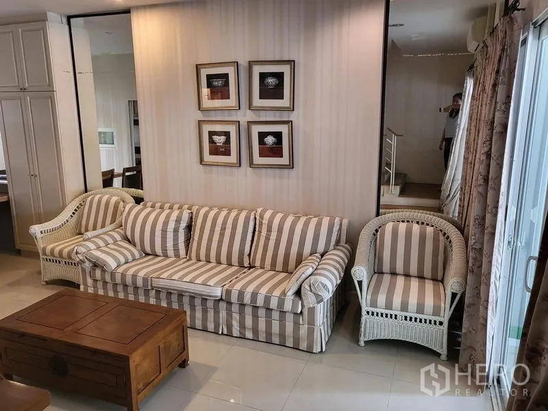 联排别墅 出租在Wang Thonglang, Bangkok - 舒适客厅，条纹沙发组、木质茶几与墙面装饰画