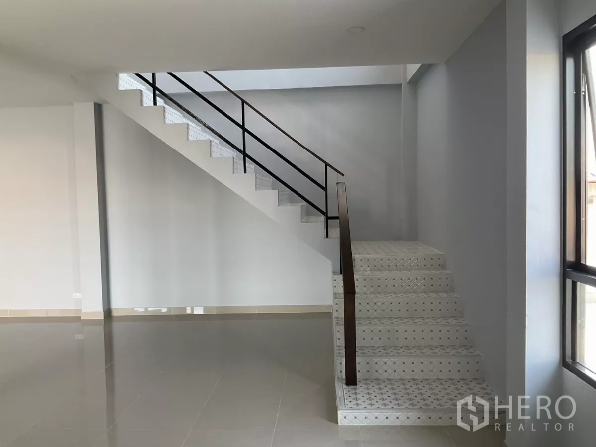Factory for sale in Samut Sakhon - Staircase with metal handrail in a bright office area with large window.