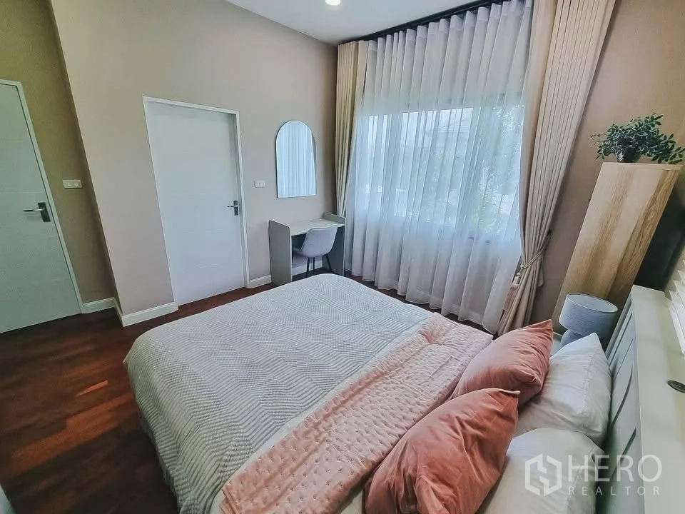 独栋房屋 for rent or sale in Bang Phli, Samut Prakan - 卧室配高窗帘、书桌与粉色系床品。