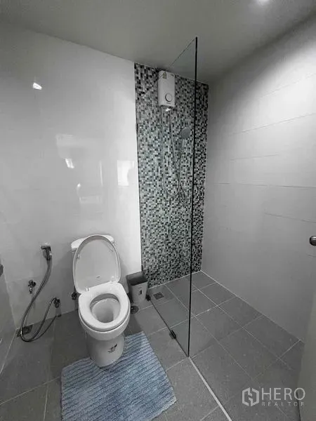 Shophouse for rent in Watthana, Bangkok - Modern bathroom with a glass shower partition and mosaic-tiled feature wall.
