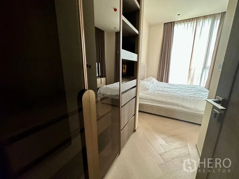 Condominium for rent - Walk-in closet corridor with mirrored wardrobes and shelving opening to a sunlit bedroom.