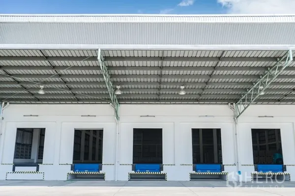 Warehouse for rent in Chon Buri - Modern warehouse loading bays with dock levelers under a wide metal canopy.