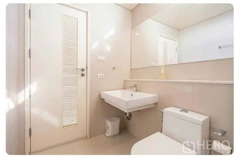 คอนโด ขายในWatthana, Bangkok - ห้องน้ำโทนขาวสะอาด กระจกบานใหญ่ อ่างล้างหน้าและโถสุขภัณฑ์