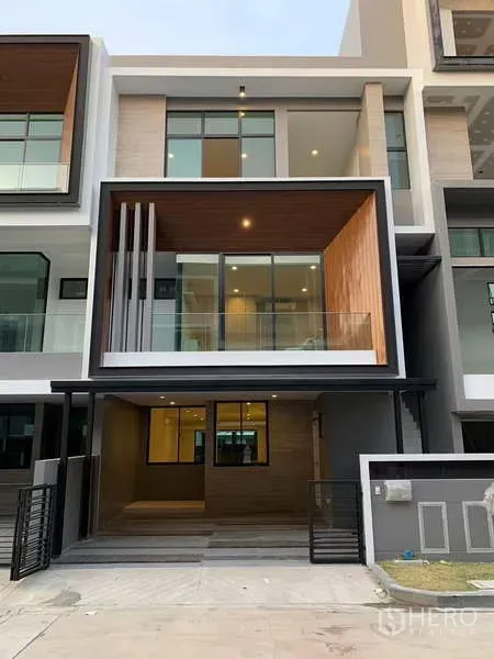 Townhouse for rent or sale in Saphan Sung, Bangkok - Modern three-storey townhouse facade with balcony, large windows and covered carport.
