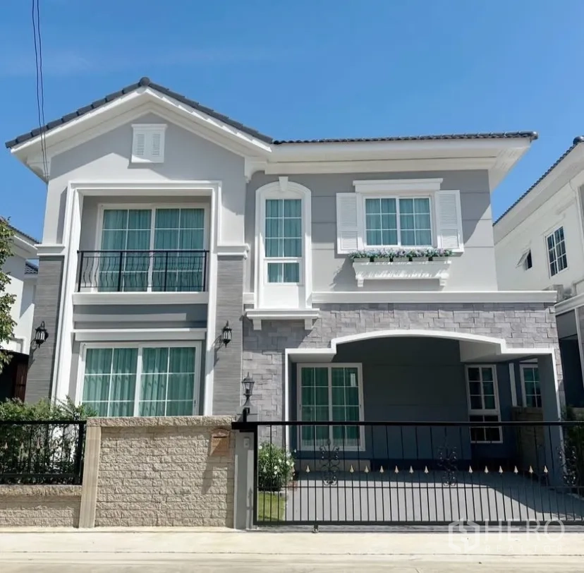 独立式住宅 出租在Mueang Samut Prakan, Samut Prakan - 两层现代独栋别墅外立面，带阳台、大门与有顶停车位。