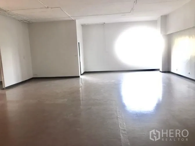 Office Space for rent in Watthana, Bangkok - Sunlit open-plan workspace with a large window and higher ceiling.