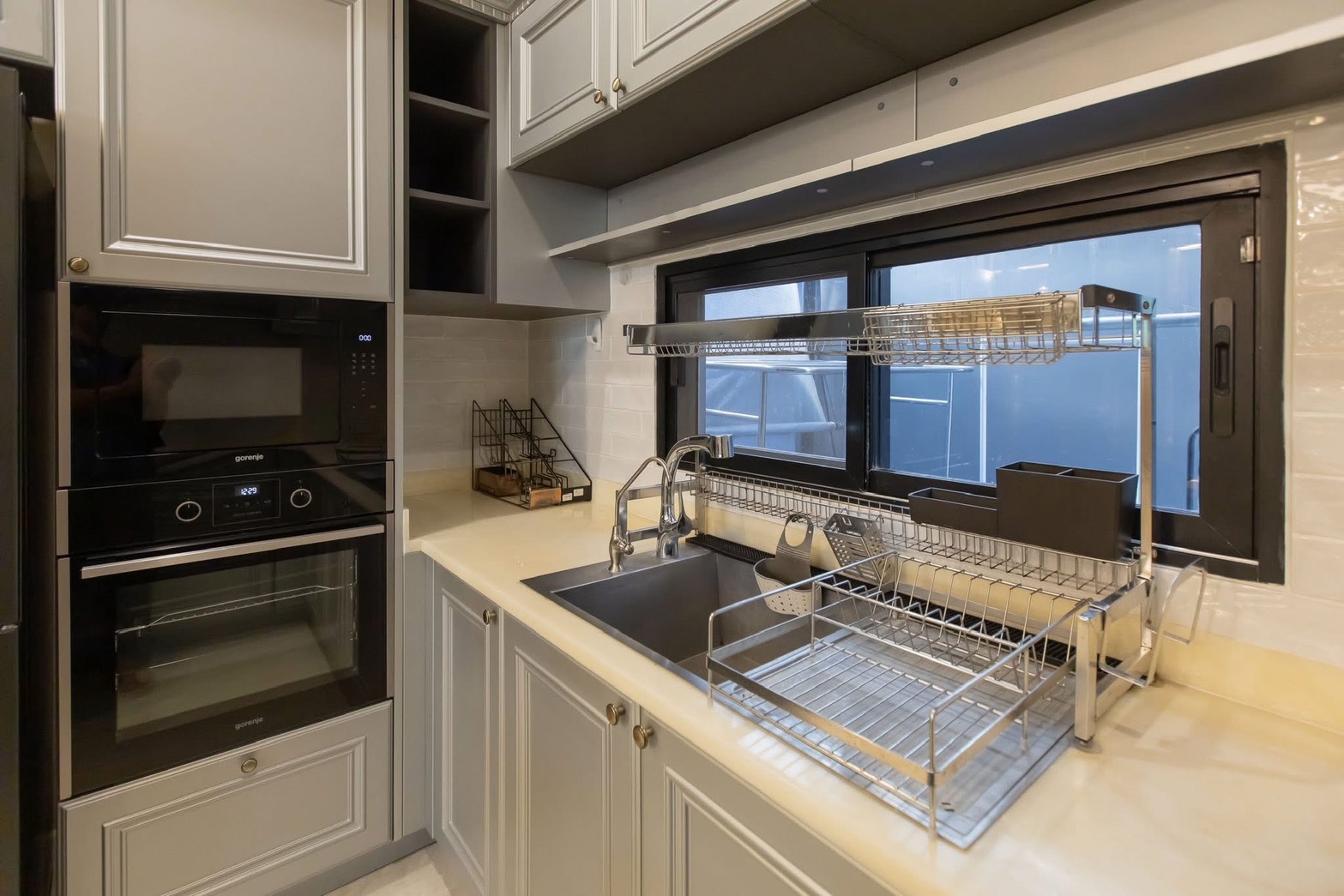 Detached House for rent in Lat Phrao, Bangkok - Close-up of the sink area with dish racks by the window and stacked oven-microwave.