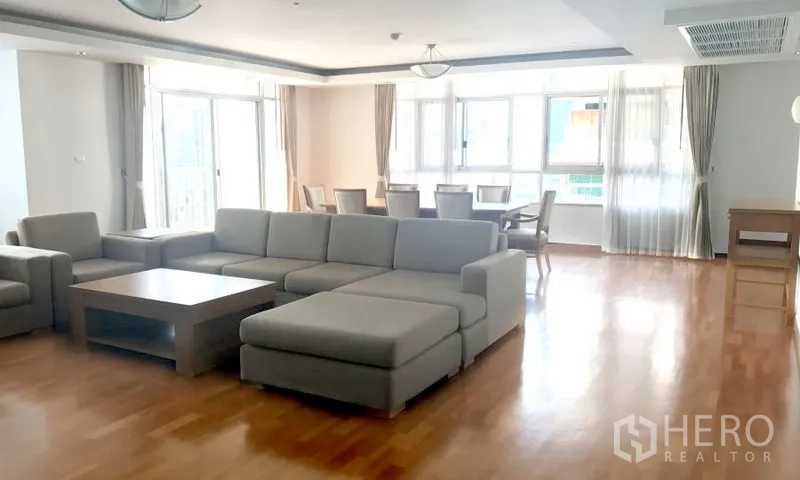 房间 出租在Watthana, Bangkok - 采光充足的客餐厅，L形沙发、木地板和大窗户。