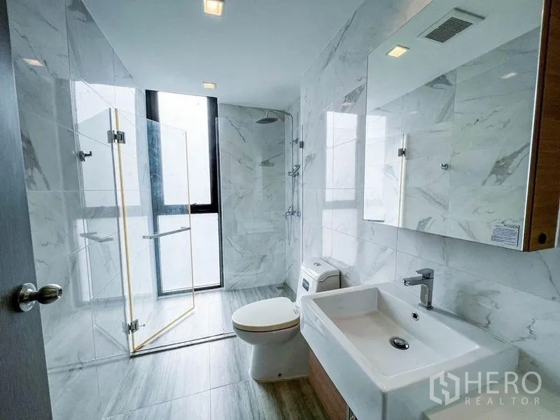 คอนโด ขายในHuai Khwang, Bangkok - ห้องน้ำที่สอง มีส่วนอาบน้ำกระจก หน้าต่างบานสูง ผนังลายหินอ่อน และอ่างล้างหน้า