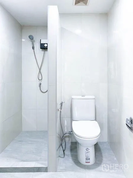 Condominium for rent or sale in Khlong Toei, Bangkok - Modern white bathroom with walk-in shower and toilet.