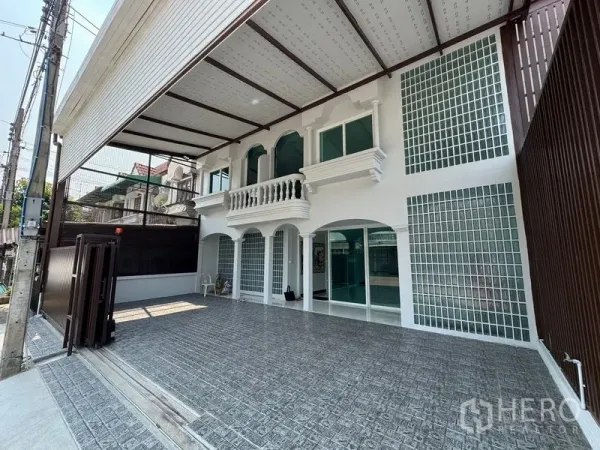 带办公室的家 出租在Bueng Kum, Bangkok - 两层白色商住两用房前的宽阔车道与有顶车棚。