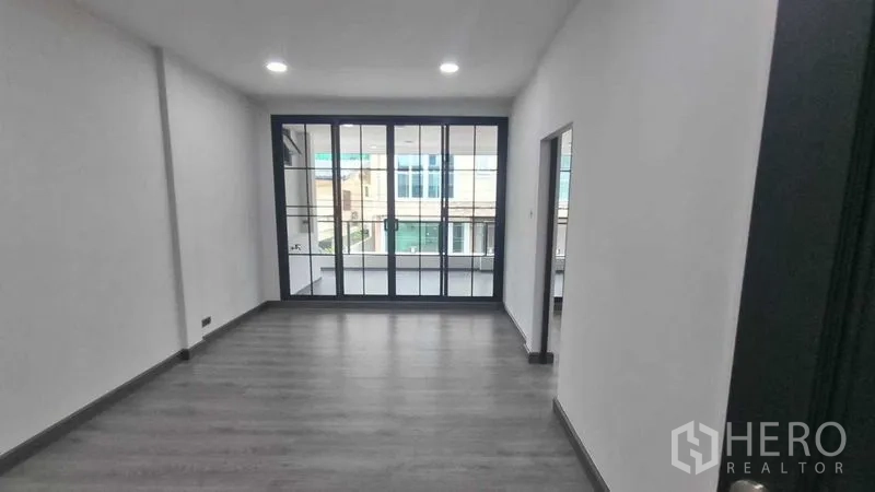 联排别墅 出租在Khlong Toei, Bangkok - 楼上房间，黑框推拉门通往阳台。