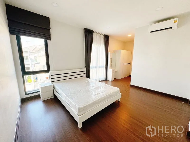 บ้าน ให้เช่าในBang Phli, Samut Prakan - ห้องนอนสว่าง เตียงคู่ พื้นไม้ หน้าต่างสูงพร้อมผ้าม่านและแอร์
