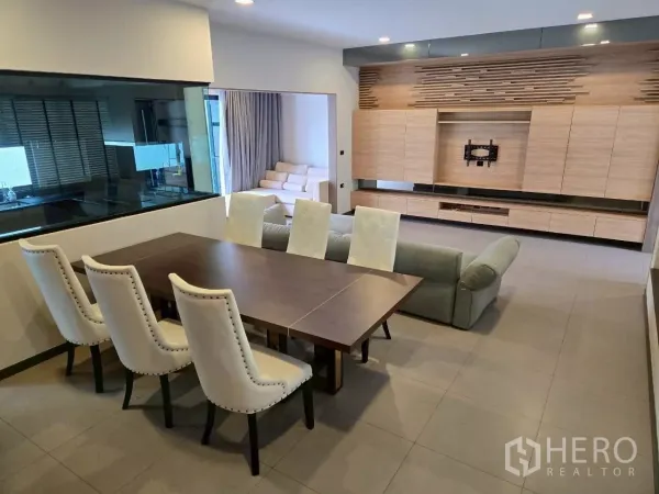 联排别墅 出租在Bang Phli, Samut Prakan - 餐桌临玻璃厨房窗，正对浅木色定制电视墙与储物柜。