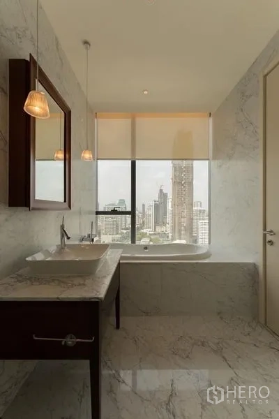 Condominium for rent in Watthana, Bangkok - Marble bathroom with vanity and bathtub set beneath a large window framing Bangkok city views.