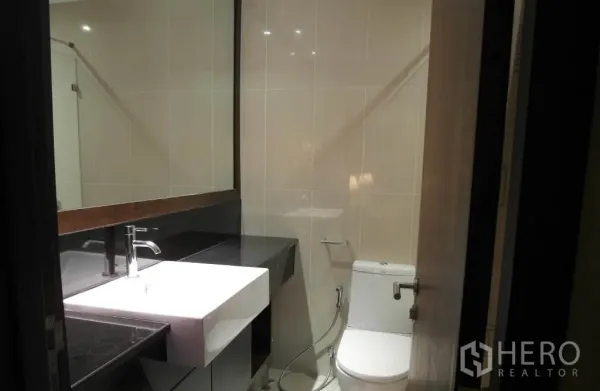 Condominium for rent or sale in Sathon, Bangkok - Contemporary bathroom with large mirror, square basin vanity and toilet.