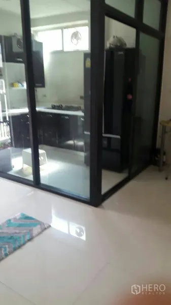 Townhouse for rent in Suan Luang, Bangkok - Glass-enclosed kitchen with black cabinets, gas cooktop and a large fridge at Noble Cube Suan Luang.