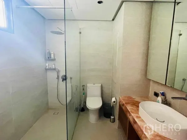 公寓 出租或出售在Watthana, Bangkok - 现代浴室，玻璃隔断雨淋花洒、马桶、大镜柜与石质台面。