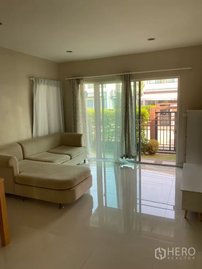 บ้าน ให้เช่าหรือขายในSuan Luang, Bangkok - ห้องนั่งเล่นสว่าง โซฟาเข้ามุม พื้นเงา ประตูกระจกบานเลื่อนออกสู่สวน