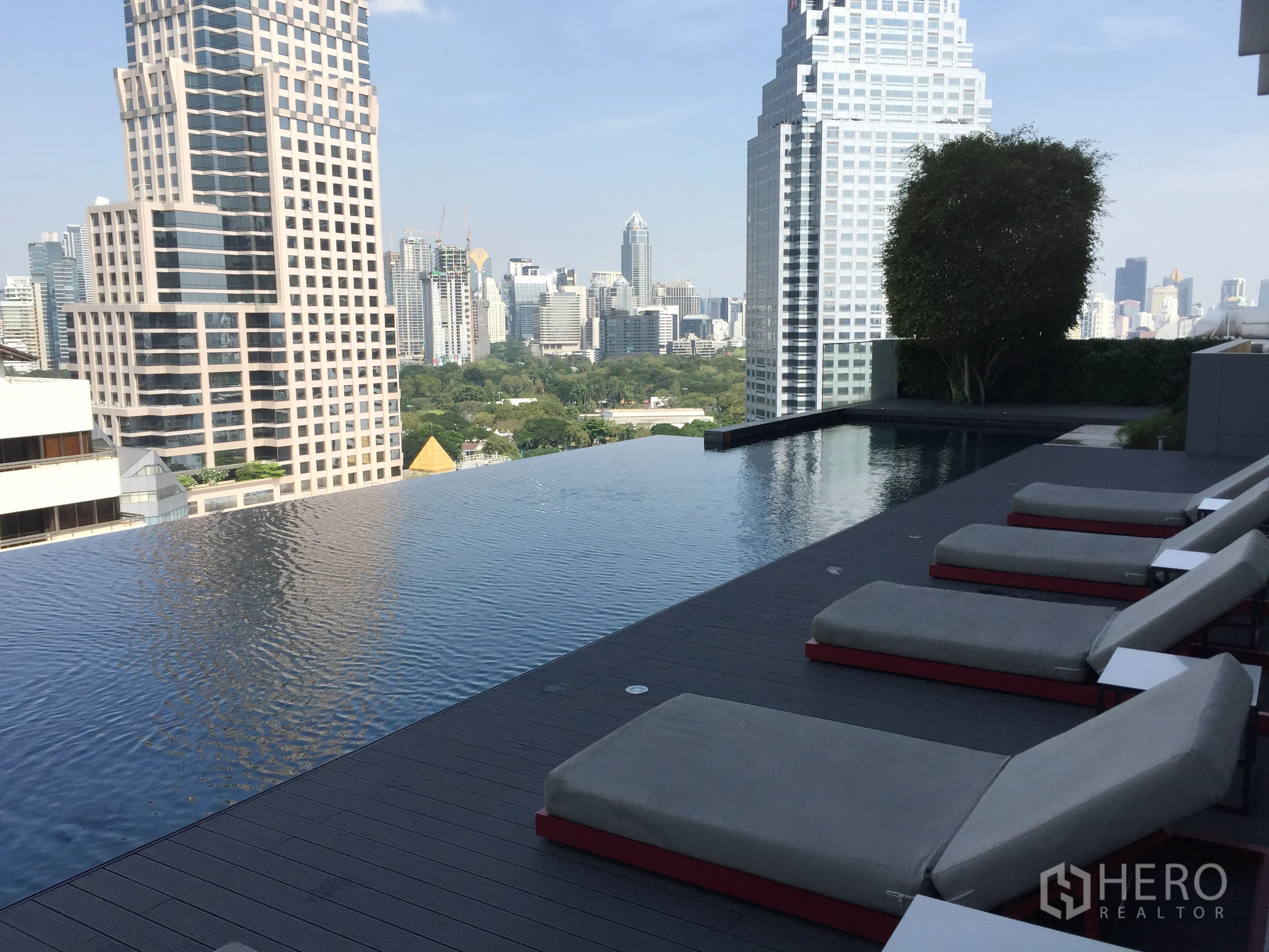 Condominium for rent in Bang Rak, Bangkok - Rooftop infinity pool with sun loungers and skyline views toward Lumpini Park.