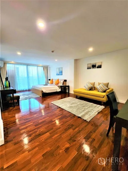 Condominium for rent in Bang Rak, Bangkok - Oversized bedroom suite with yellow sofa, work desk, and balcony doors.