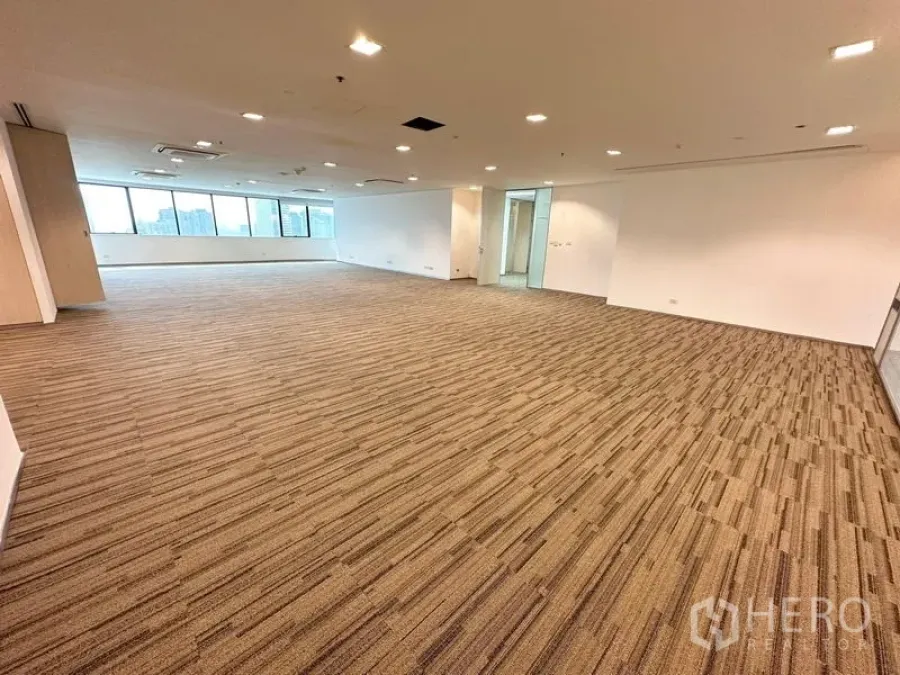 办公空间 出租在Watthana, Bangkok - 开放办公区，弧形落地窗墙、吊装灯具与中性色地毯。