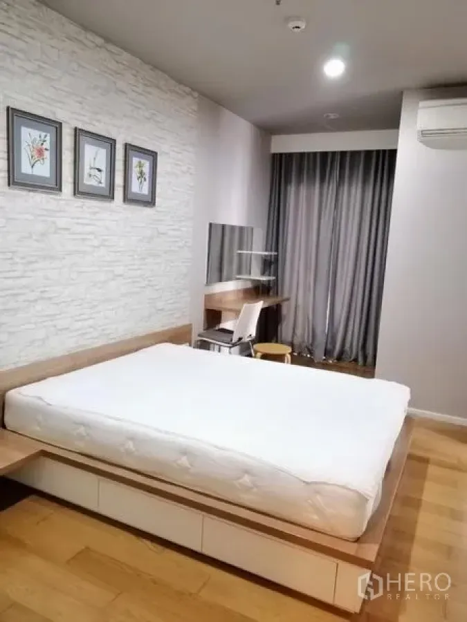 Condominium for rent in Watthana, Bangkok - Master bedroom with platform bed, wood flooring and a study desk by the window