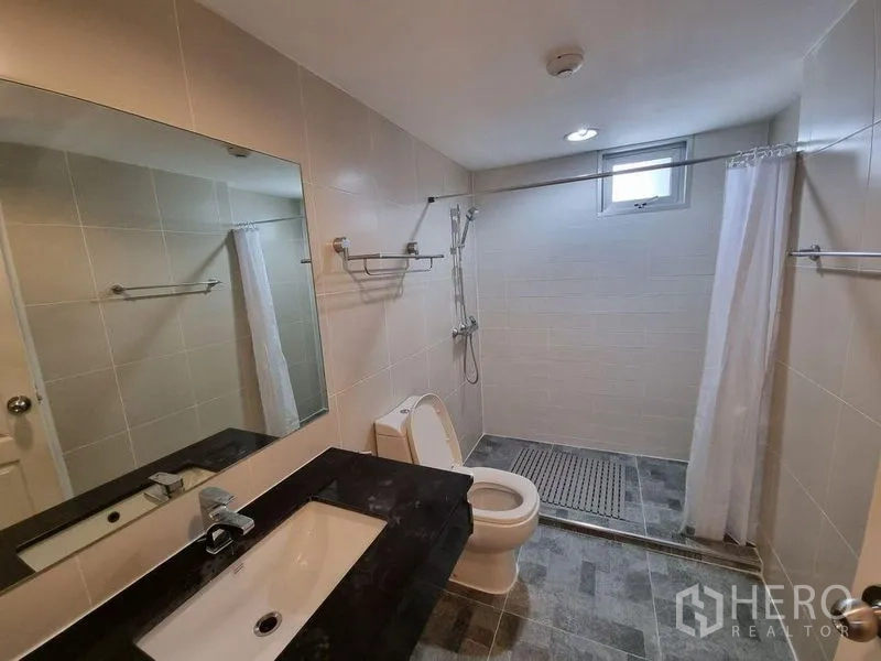 公寓 出租在Huai Khwang, Bangkok - 卫浴配大镜、洗手台、坐便与步入式淋浴区。